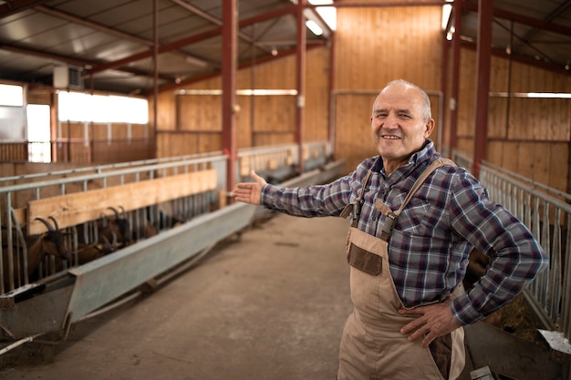 Retrato de exitoso agricultor sonriente mostrando su granja y animales domésticos