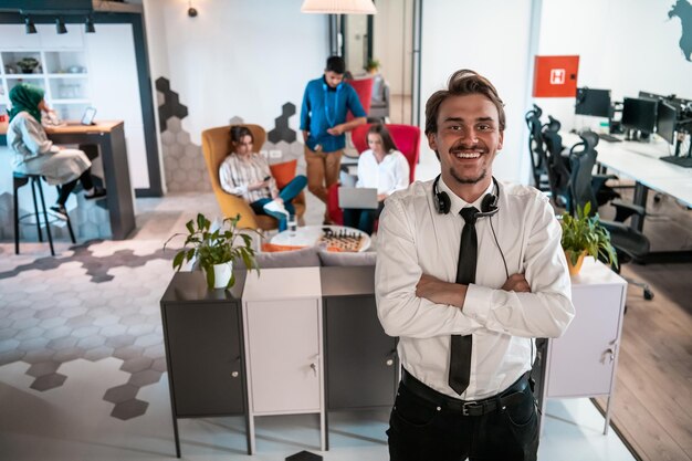 Retrato de un exitoso empresario con auriculares alrededor del cuello y colegas en segundo plano en una oficina de inicio ocupada. foto de alta calidad