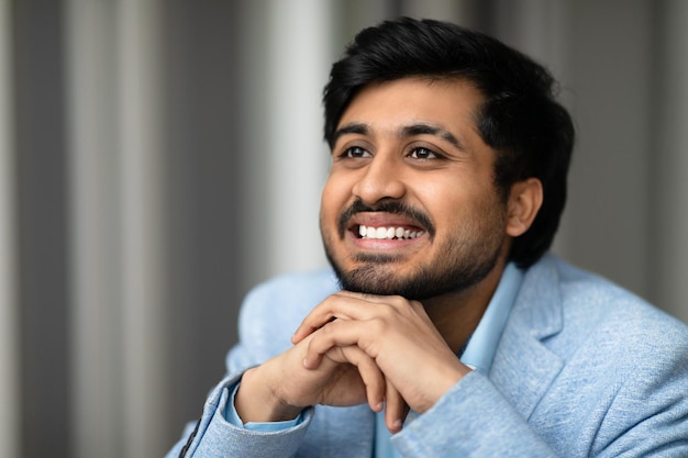 Retrato de un exitoso empresario de Oriente Medio sonriente mirando a un lado en el interior