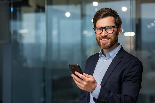 Retrato de un exitoso hombre de negocios maduro inversionista con gafas y barba sonriendo y mirando