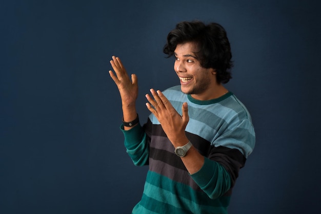 Retrato de un exitoso joven alegre señalando y presentando algo con la mano o el dedo con una cara sonriente feliz