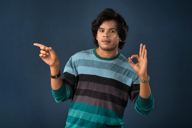 Retrato de un exitoso joven alegre señalando y presentando algo con la mano o el dedo con una cara sonriente feliz