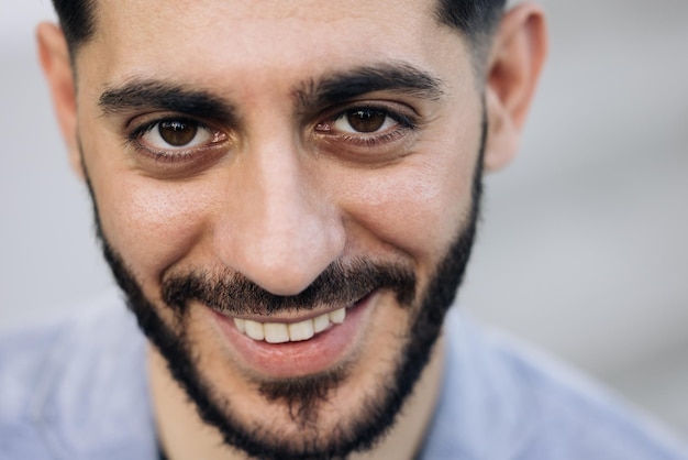 Retrato facial de atractivo joven caucásico mestizo alegre en traje formal de negocios sonriendo