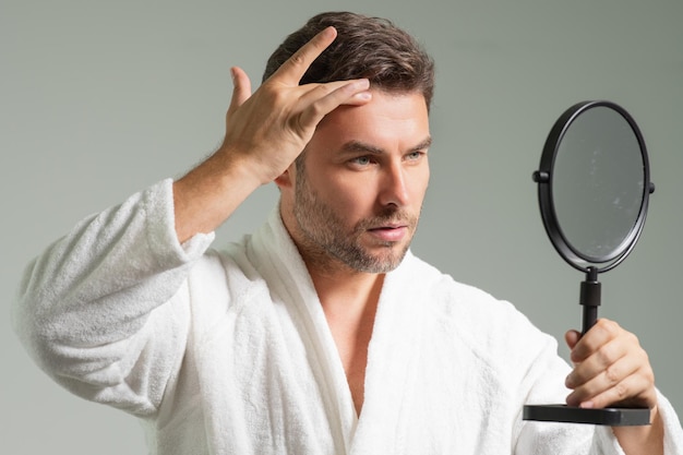 Retrato facial de beleza de um homem bonito aplicando creme facial creme hidratante para a pele para máscara masculina