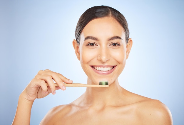 Retrato facial dental y mujer con cepillo de dientes en estudio aislado en un fondo azul Carillas de bienestar bucal y modelo femenino feliz sosteniendo producto para cepillarse los dientes, limpieza e higiene bucal