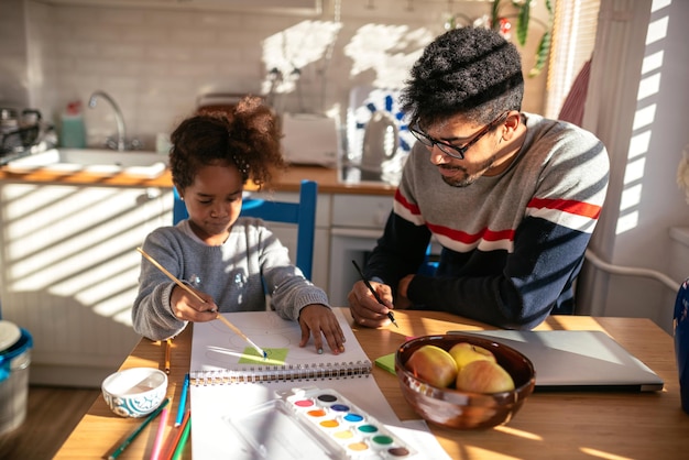 Retrato de una familia afroamericana que se une mientras dibuja en la cocina.