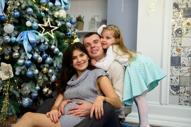 Retrato de familia amable mirando a cámara en la noche de Navidad.