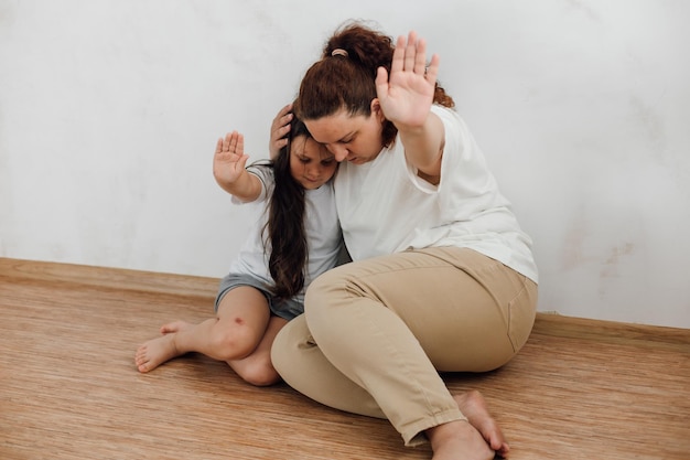 Retrato de familia asustada Joven madre asustada mujer abrazando a su pequeña hija protegiendo el abuso
