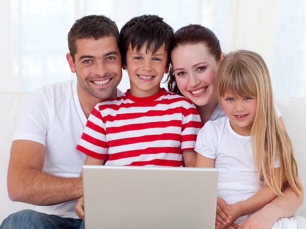 Retrato de familia en casa usando una computadora portátil