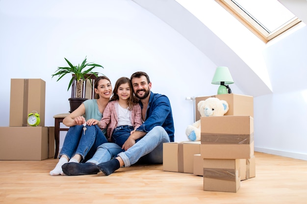 Retrato de familia caucásica sonriente feliz en su nueva casa y cajas de cartón a su alrededor.