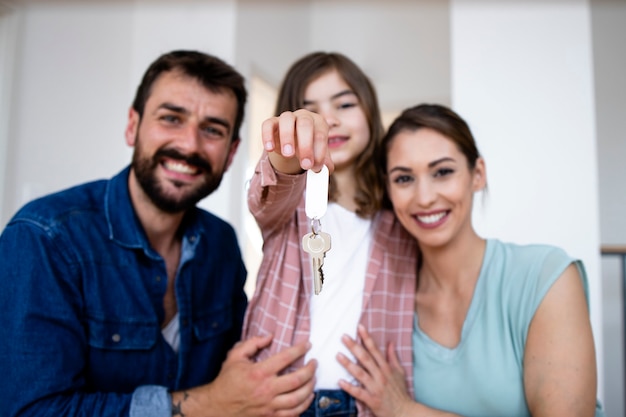 Foto retrato de familia caucásica sonriente con hija sosteniendo llaves de su nuevo hogar.