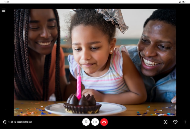 Retrato de una familia celebrando un cumpleaños en línea en una videollamada con familiares y amigos mientras se queda en casa. Nuevo concepto de estilo de vida normal.