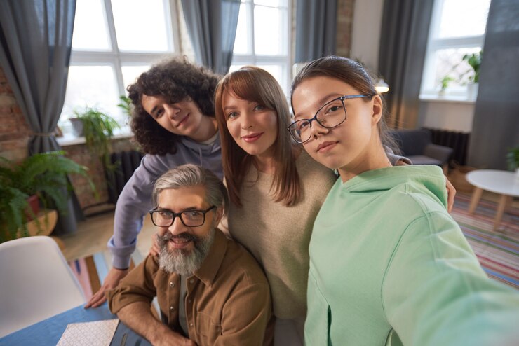 Retrato de familia de cuatro sonriendo a la cámara haciendo retrato selfie juntos en la sala de estar en casa