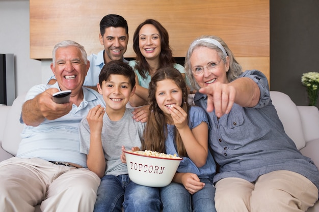 Retrato de familia extendida feliz viendo la televisión en la sala de estar