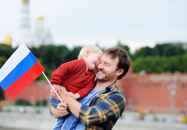 Foto retrato de familia feliz con la bandera rusa con el kremlin de moscú