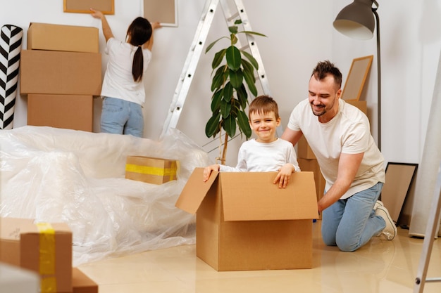 Retrato de familia feliz con cajas de cartón en casa nueva en el día de la mudanza