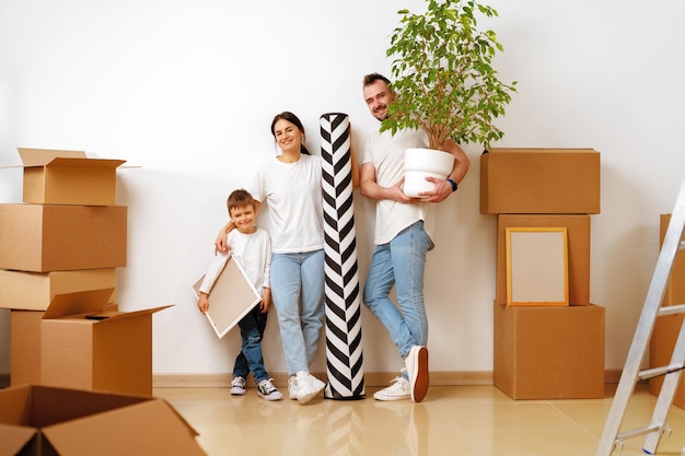 Retrato de familia feliz con cajas de cartón en casa nueva en el día de la mudanza