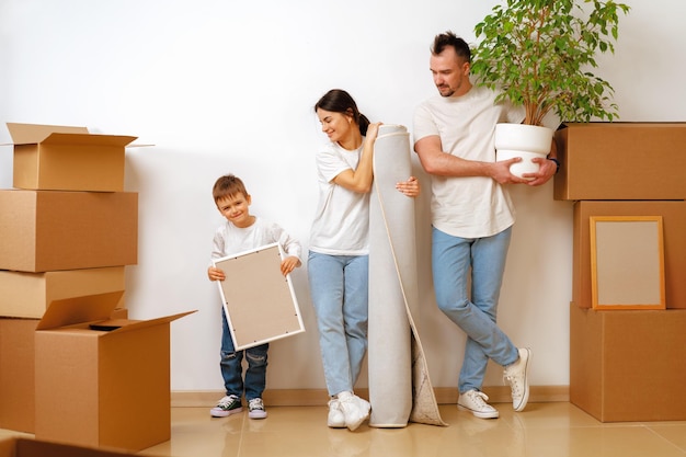 Retrato de familia feliz con cajas de cartón en casa nueva en el día de la mudanza