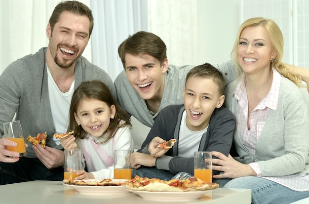 Retrato de familia feliz en casa con pizza