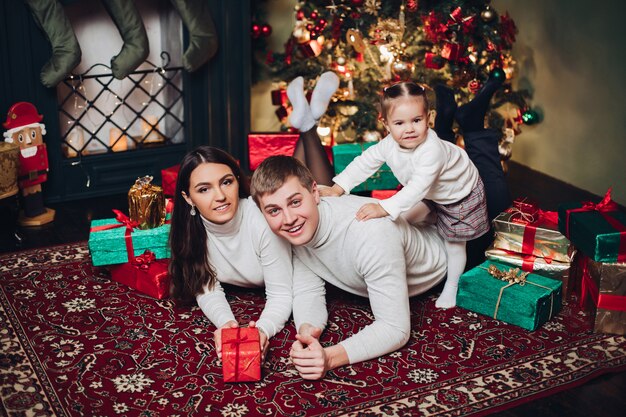 Retrato de familia feliz del Cáucaso con regalos posando junto a la chimenea.