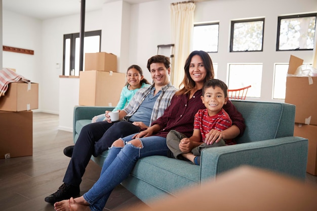 Retrato de familia feliz descansando en un sofá rodeado de cajas en un nuevo hogar el día de la mudanza