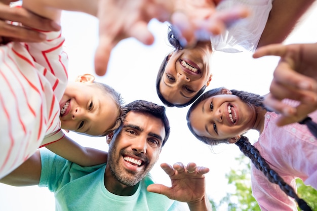 Retrato de familia feliz formando huddle en el parque