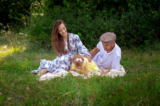 Retrato de familia feliz juega con su pequeña hija en el prado verde