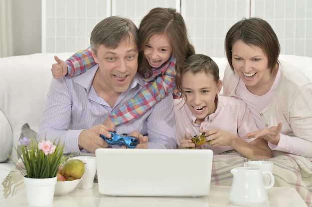 Retrato de familia feliz jugando en el portátil en casa