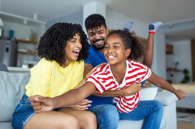 Retrato de familia feliz Madre padre alegre y su linda hija posando en la sala de estar en casa niña sentada en el regazo de papá espacio libre