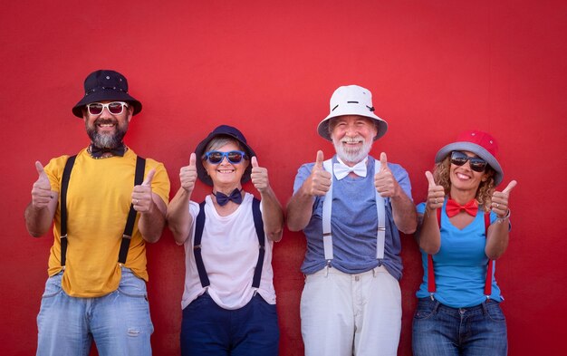 Foto retrato de una familia feliz y a la moda gestando los pulgares hacia arriba contra la pared roja