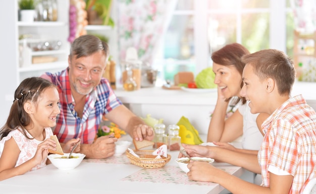 Retrato de una familia feliz con niños desayunando