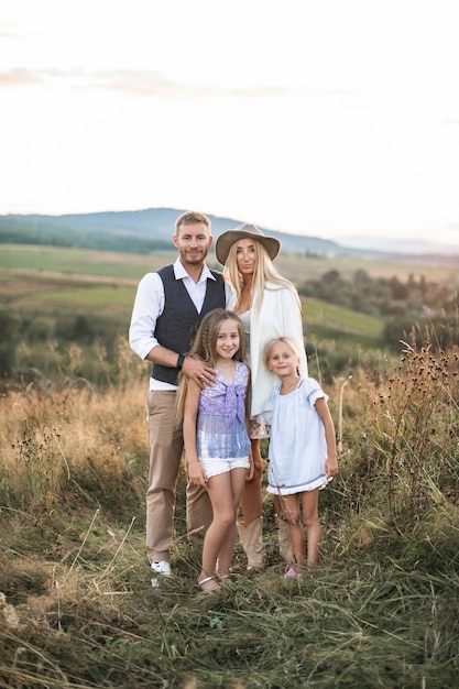 Retrato de familia feliz con niños vistiendo ropa elegante boho vaquero de pie en el campo del país