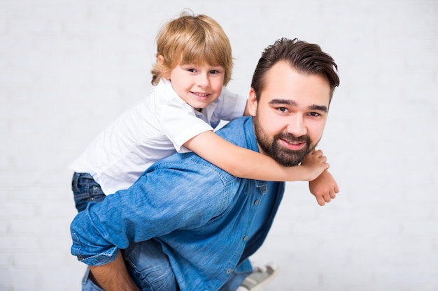 Retrato de familia feliz - padre con un lindo hijo pequeño posando sobre fondo blanco