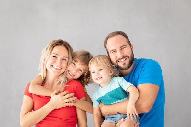 Retrato de familia feliz - padre, madre, hija e hijo - contra la superficie gris