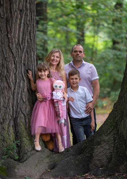 Retrato de una familia feliz papá madre hijo e hija entre un gran árbol