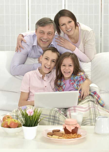 Retrato de una familia feliz con un portátil en la habitación