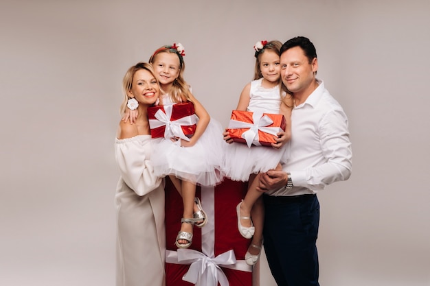 Retrato de una familia feliz con regalos en sus manos sobre un fondo beige.