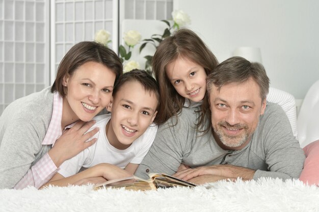 Retrato de familia feliz relajándose en casa con libro