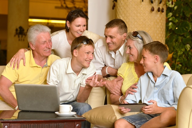 Retrato, de, un, familia feliz, sentado, con, computador portatil