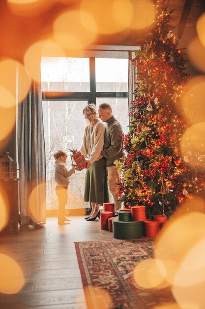 Foto retrato de una familia feliz con suéteres beige de punto esperando a papá noel en el interior