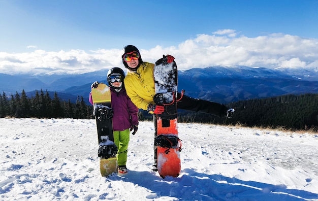 Retrato de familia feliz con tablas de snowboard mirando a la cámara sobre fondo azul.