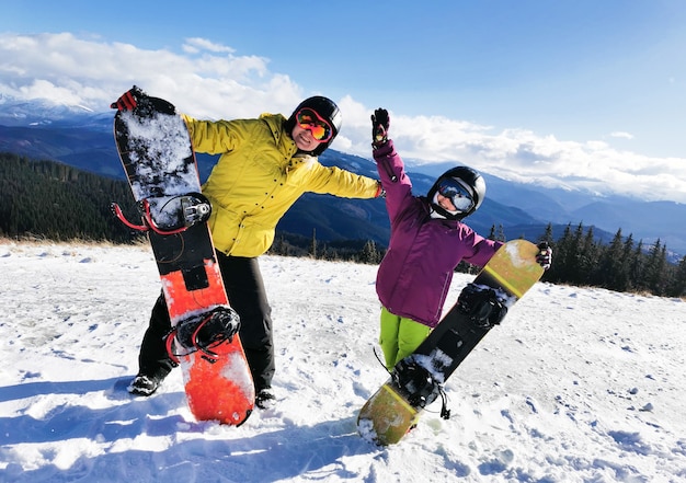 Retrato de familia feliz con tablas de snowboard mirando a la cámara sobre fondo azul.