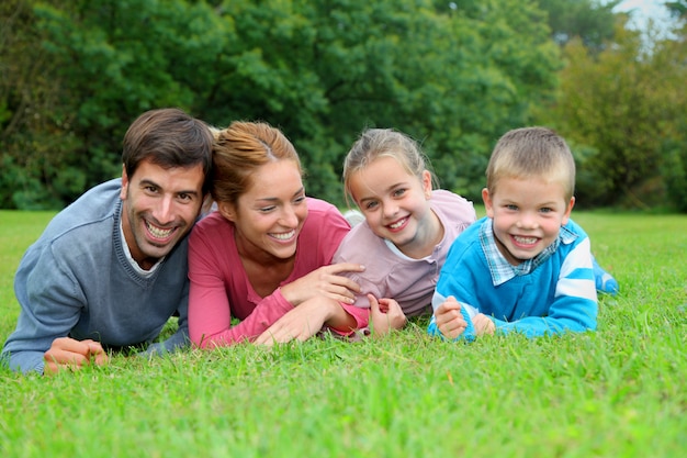 Foto retrato de familia feliz tumbado en la hierba