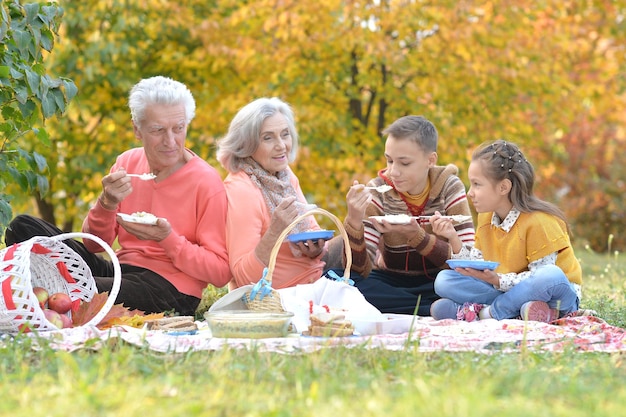 Retrato de familia haciendo un picnic en el parque en otoño