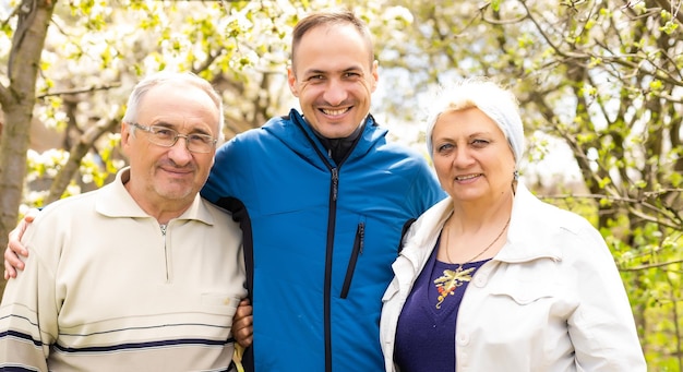 Retrato de familia con hijo adulto al aire libre.