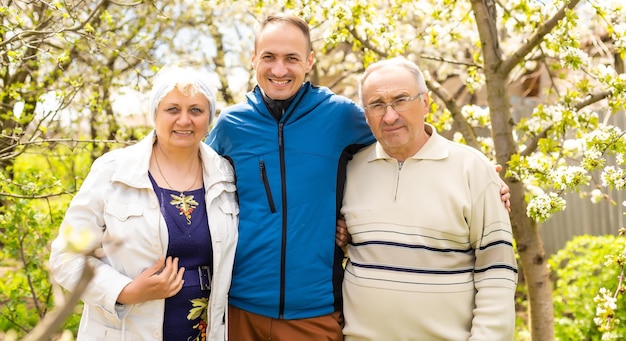 Retrato de familia con hijo adulto al aire libre.