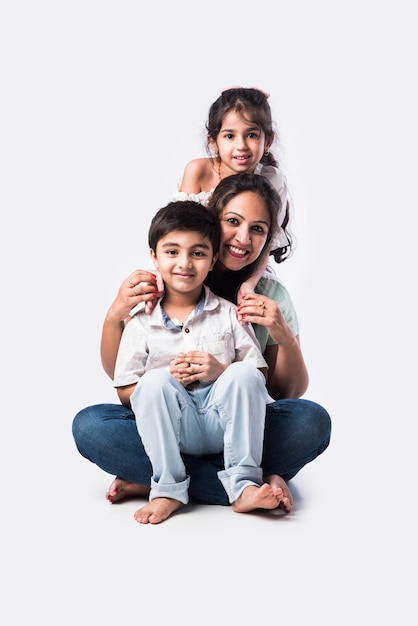 Retrato de familia joven asiática india de cuatro sentados en harina blanca contra el fondo blanco, mirando a la cámara