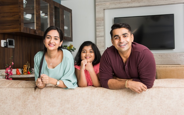 Foto retrato de familia joven asiática india feliz mientras está sentado en el sofá, acostado en el suelo o sentado contra la pared