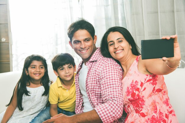 Retrato de familia joven y feliz de Asia India, sentado en el sofá en casa