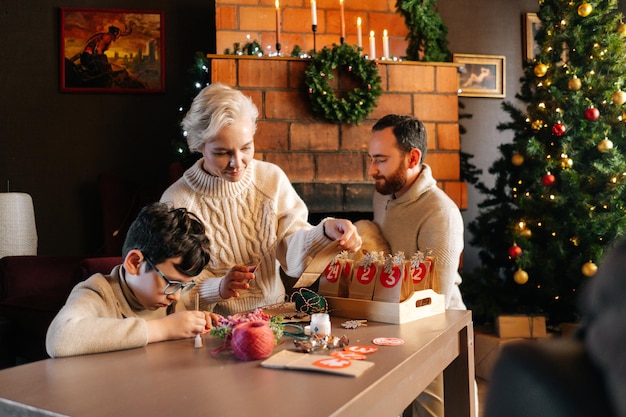 Retrato de familia joven feliz haciendo calendario de Adviento de Navidad juntos sentados a la mesa en